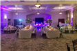 Indoor reception with long tables and purple uplighting 
