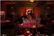 Large floral arrangements on round tables with red uplighting