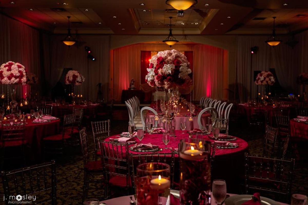 Large floral arrangements on round tables with red uplighting